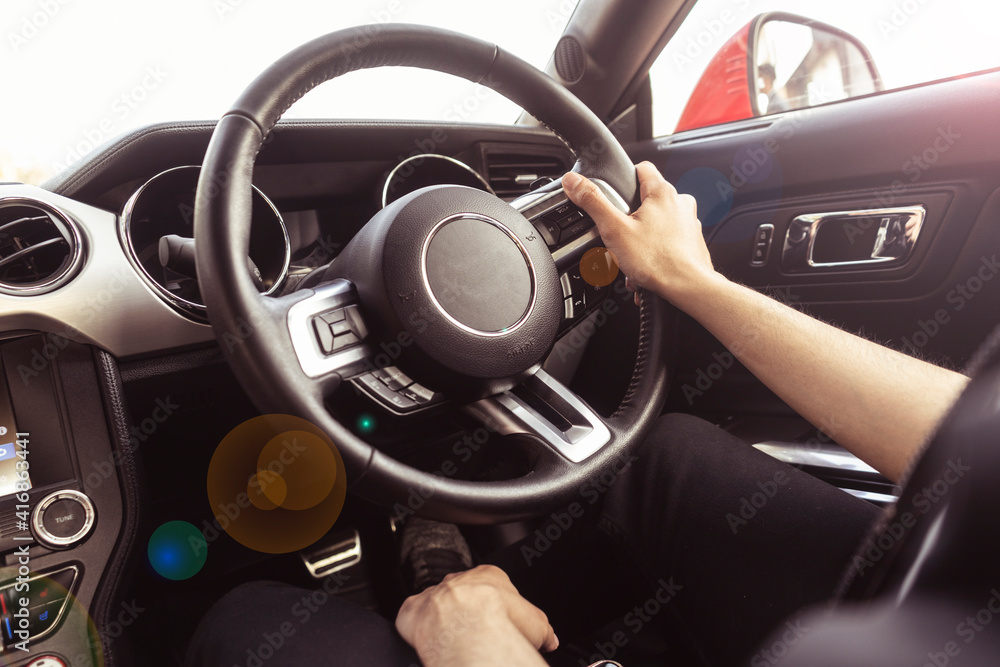 Close up of hands holding the steering wheel of a car. Interior of a luxury car.