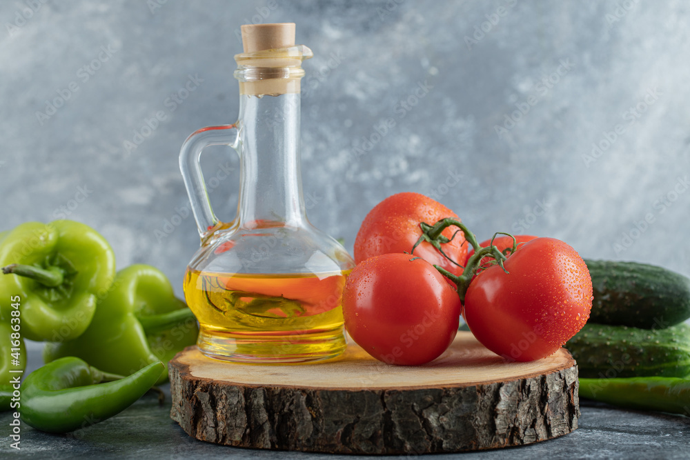 Close up photo of red tomato with green peppers and bottle of oil Close up photo of red tomato with green peppers and bottle of oil