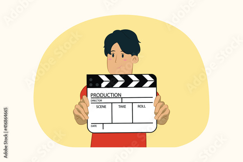Young man holding in hands classic black film making clapperboard concept