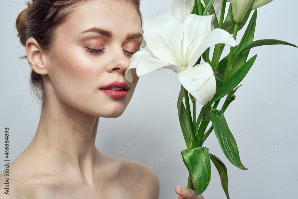 Beautiful girl with a bouquet of white flowers on a light background naked shoulders clean skin spring Beautiful girl with a bouquet of white flowers on a light background naked shoulders clean skin spring