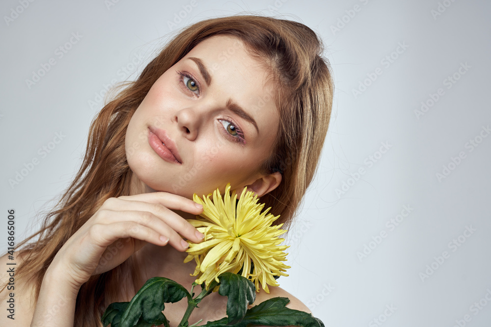 Portrait of a beautiful woman with a yellow flower on a light background cropped with Copy Space Model