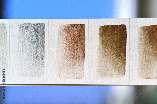Fragment of a color palette with metallic colors of watercolor paints.