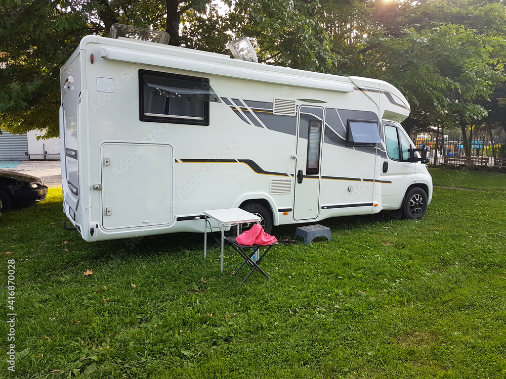 caravan car on the camping green grass and tress beside lake