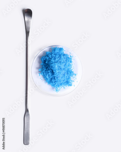 Copper(II) sulfate in Chemical Watch Glass placed next to the stirring rod on laboratory table.