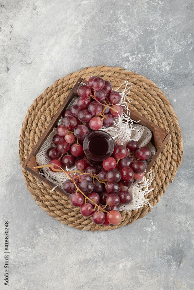 Delicious ripe grapes and glass of juice in wooden box Delicious ripe grapes and glass of juice in wooden box