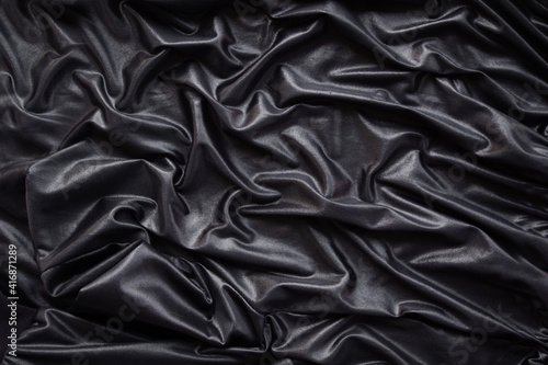 Luxurious black silk satin cloth flat lay background. black abstract smoot rippled fabric stylish top view wallpaper. for add text or products for presentation.