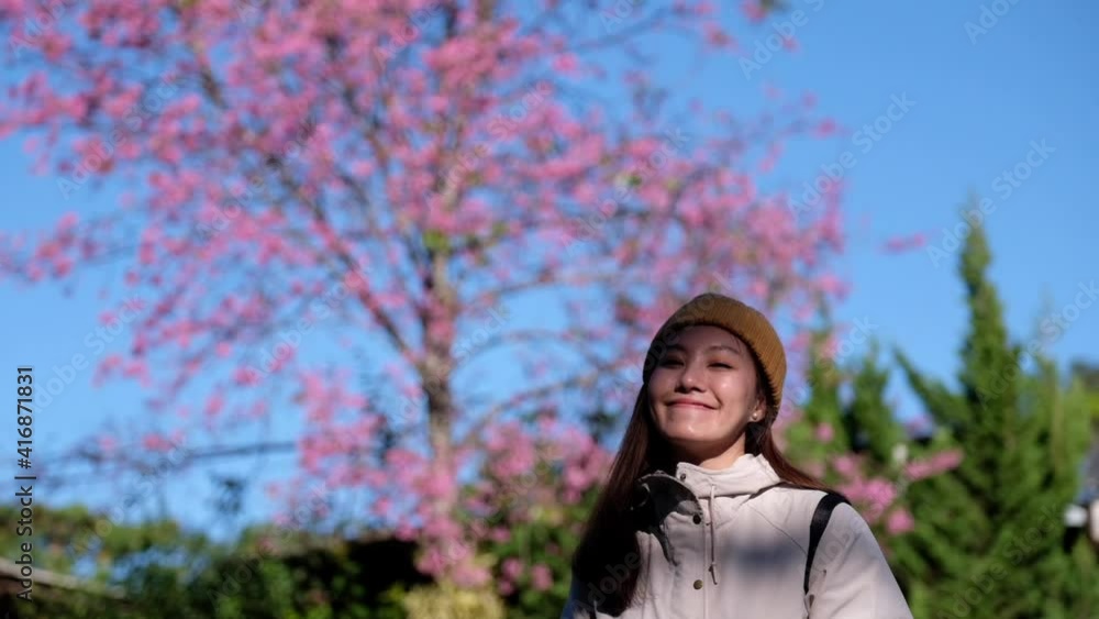 Slow motion of a beautiful young asian woman with pink cherry blossom flower in background Slow motion of a beautiful young asian woman with pink cherry blossom flower in background