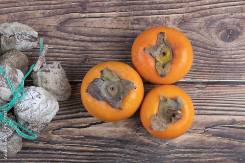 Tasty fuyu persimmons and dried persimmons on wooden surface