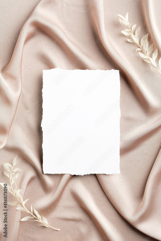 Blank white paper card on satin fabric with dried flowers. Flat lay, top view, copy space. Wedding invitation card design. Blank white paper card on satin fabric with dried flowers. Flat lay, top view, copy space. Wedding invitation card design.