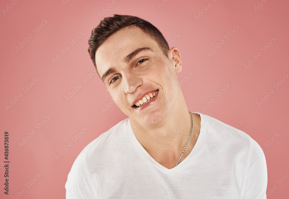 Portrait of a cheerful guy on a pink background cropped view of a white t-shirt emotions