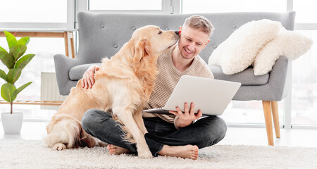 Man with laptop and golden retriever dog