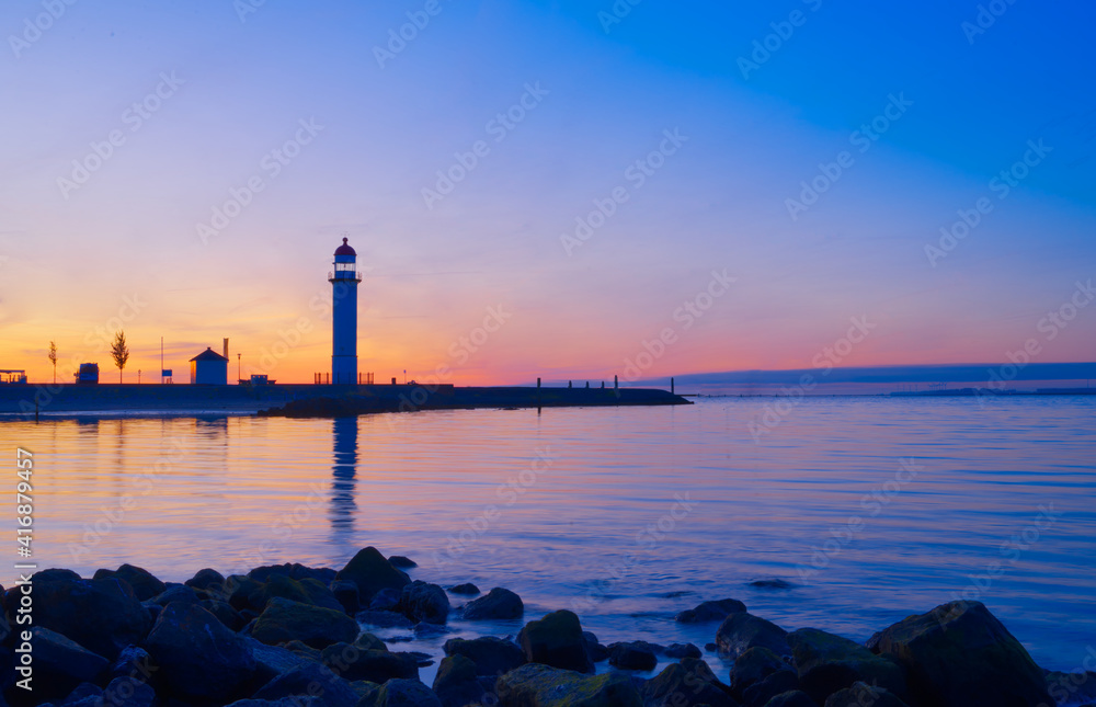 Silhouette of a lighthouse in harbor, on a sunset background