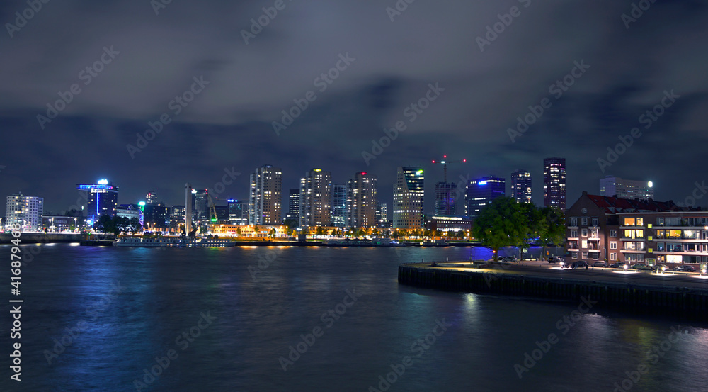 Night view of Rotterdam in Netherlands; city buildings and river under the black sky