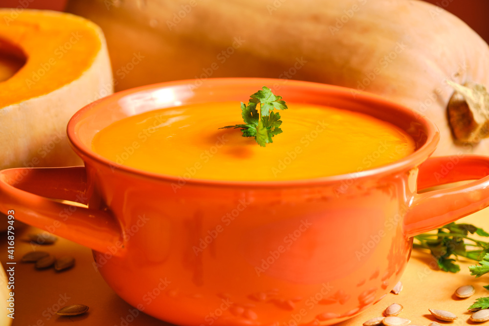 A close-up of an all-orange pumpkin puree like pumpkin with pumpkin pipes on the table and pumpkins on the decorative background, one whole and the other cut in half A close-up of an all-orange pumpkin puree like pumpkin with pumpkin pipes on the table and pumpkins on the decorative background, one whole and the other cut in half