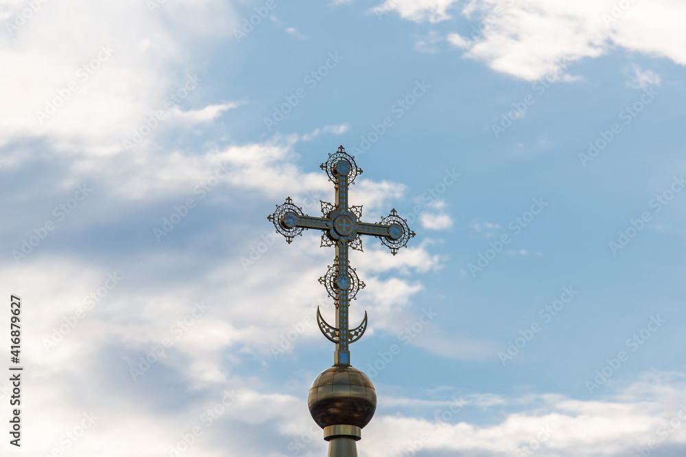 A golden cross on the dome of an Orthodox Christian church