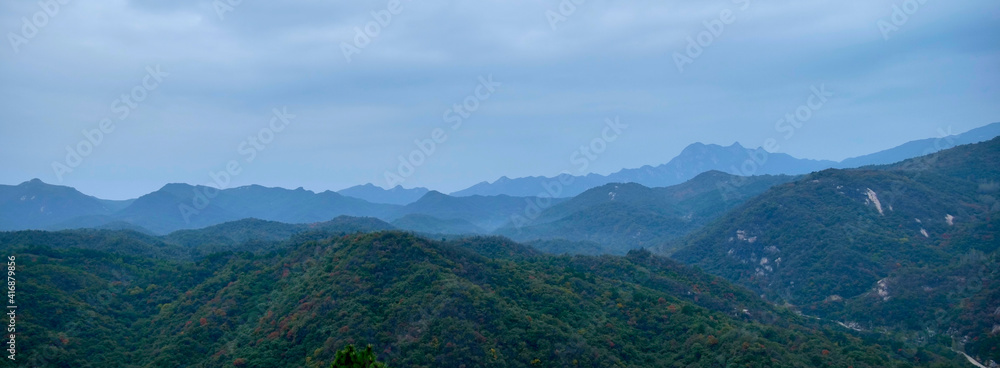 Panoramic view of green continuous mountain hills in summer; mountains and clouds on a cloudy day