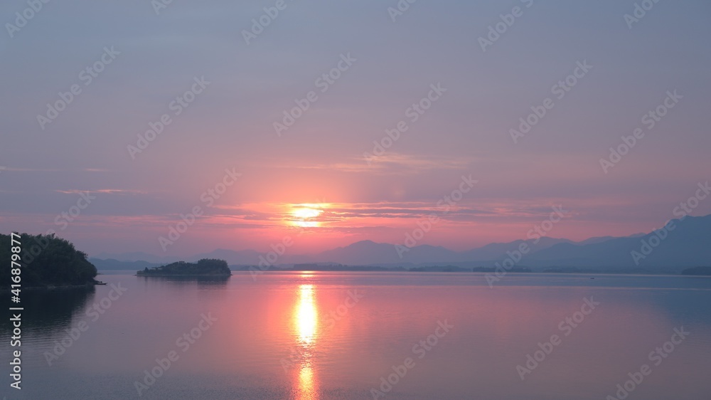 Orange sunset reflecting on the water; beautiful lake scenery in the evening