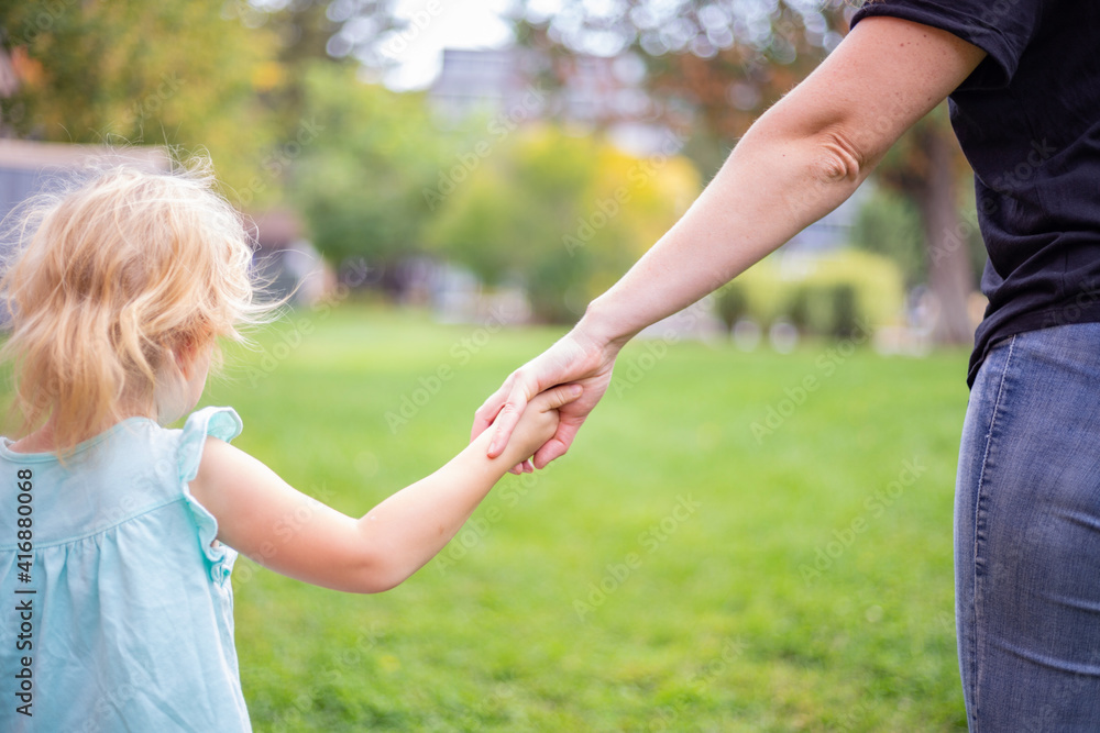 Fototapeta premium Mother and daughter holding hands. Family love and care concept.