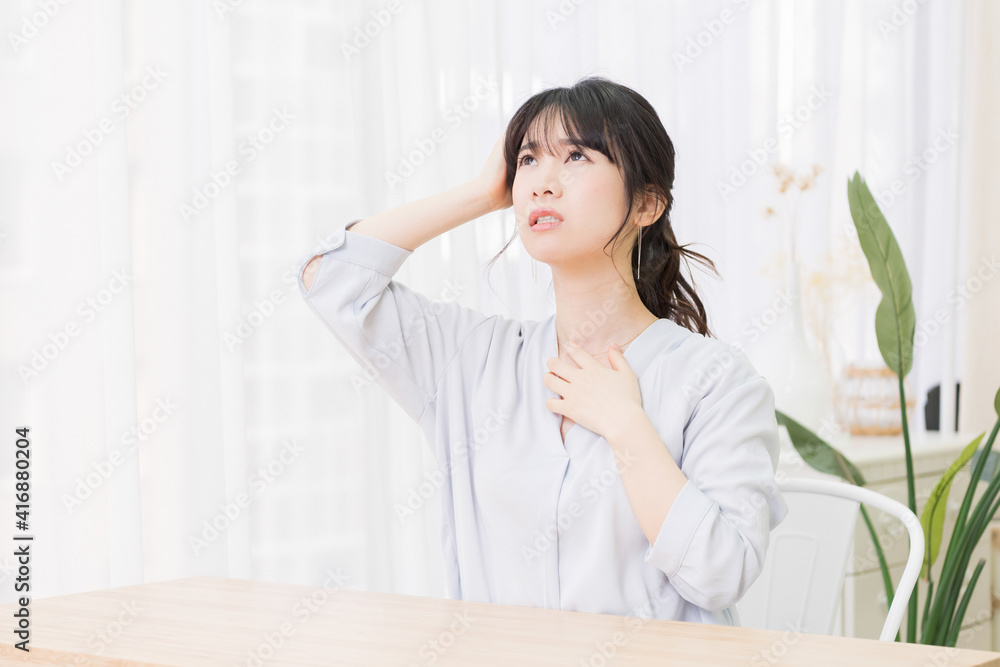 部屋で悩んでいるジェスチャーをする若い女性 部屋で悩んでいるジェスチャーをする若い女性