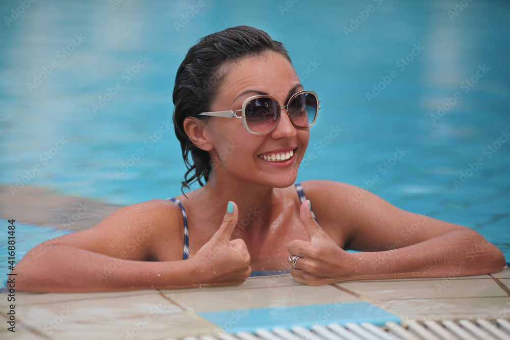 Funny young girl in sunglasses in the pool