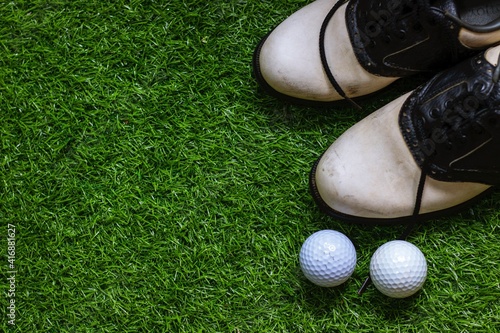 Golf shoe and golf ball flat lay on green grass