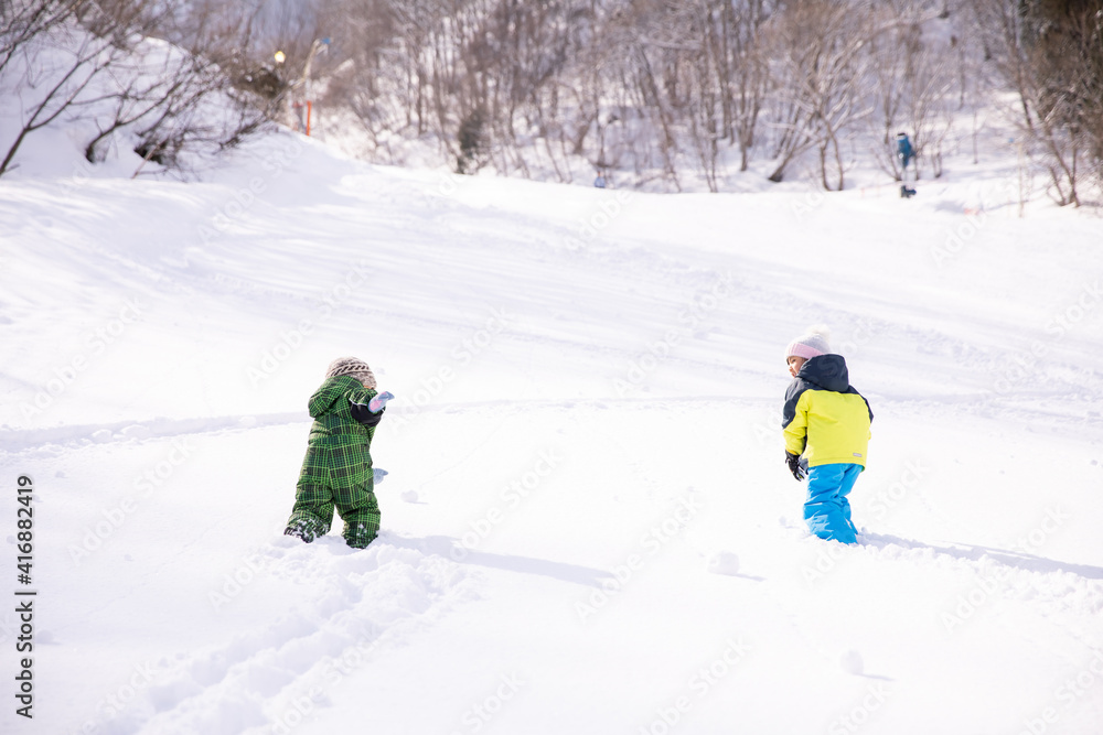 男の子と女の子がスキーウェアーを着てスキー場を登っている　winter