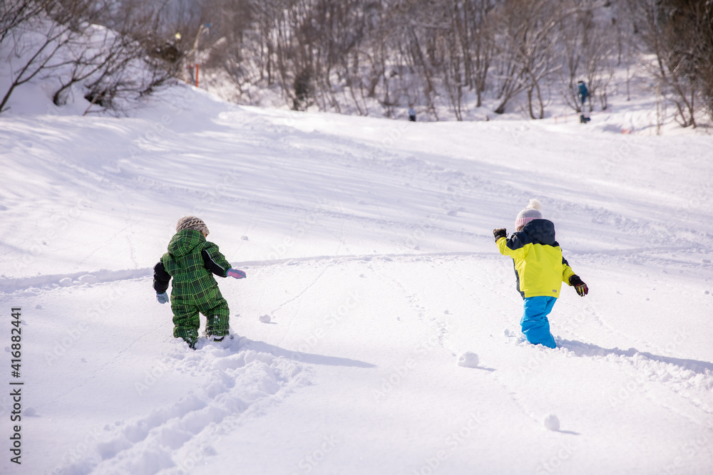 男の子と女の子がスキーウェアーを着てスキー場を登っている　winter