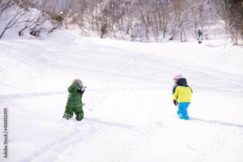 男の子と女の子がスキーウェアーを着てスキー場を登っている winter