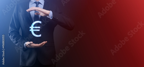 Fototapeta Naklejka Na Ścianę i Meble -  Businessman holds money coin icons EUR or Euro on dark tone background..Growing money concept for business investment and finance