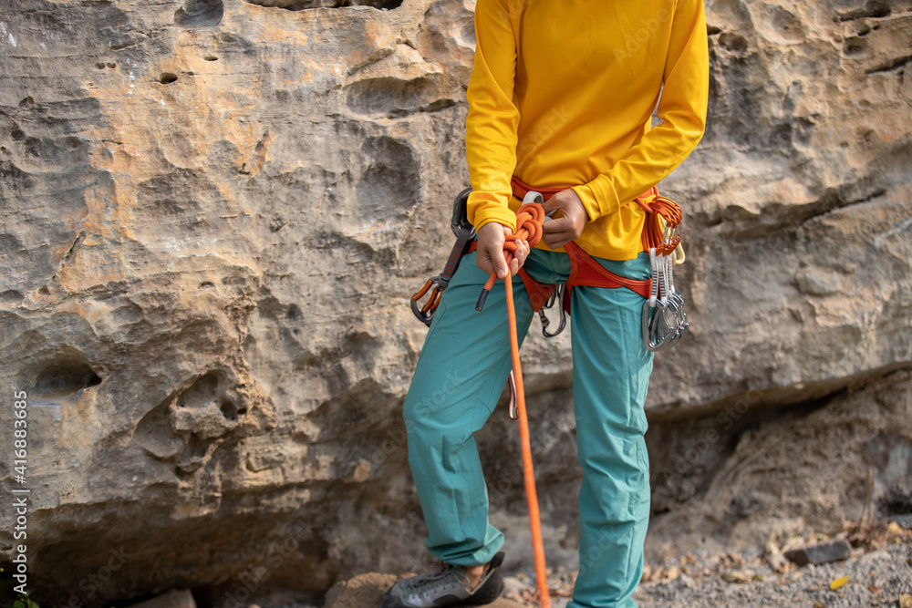 Rock climber wearing safety harness making a eight rope knot Rock climber wearing safety harness making a eight rope knot
