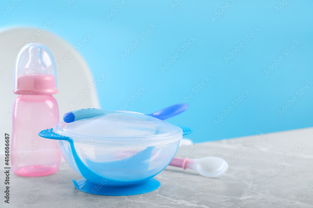 Set of plastic dishware on grey table. Serving baby food Set of plastic dishware on grey table. Serving baby food