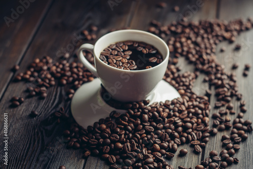 coffee beans on a wooden background and a cup on a saucer close-up macro photography