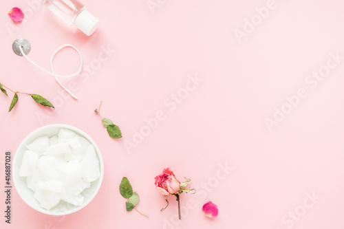 DIY concept. Wax, wick, dry roses - ingredients for making handmade candles on a pink background. Flat lay. View from above with copy space.