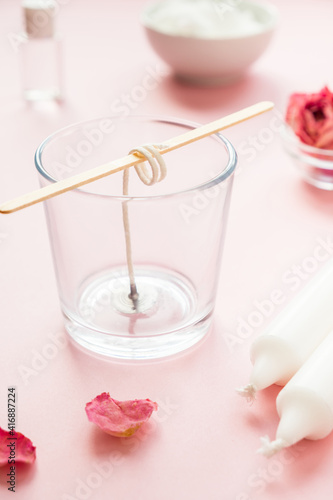 DIY concept. Wax, wick, dry roses - ingredients for making handmade candles on a pink background.