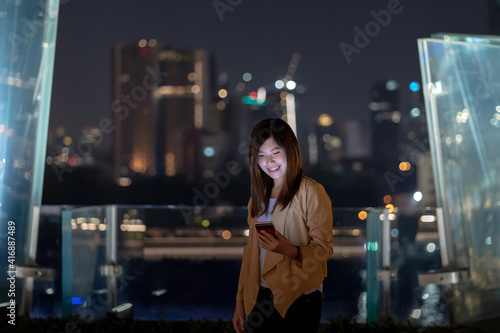 Asian businesswoman using smart mobile phone with smile action in the financial district area at bangkok river side, Thailand, technology with career concept photo