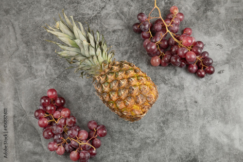Fresh red grapes with ripe pineapple on marble surface