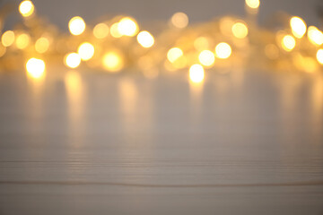 Blurred view of gold lights on white table, space for text