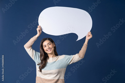 Obraz na płótnie Happy young smiling Asian woman holding copy space empty message bubbles on blue color background, thinking and specking via balloon blank paper, Private opinion for advertisement Concept w salonie