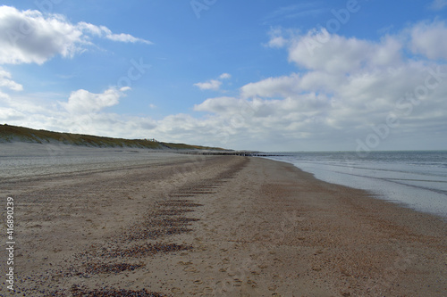 A wide open expanse of North Sea coastline and sandy beach at Domburg in the Netherlands under a blue cloudy sky.