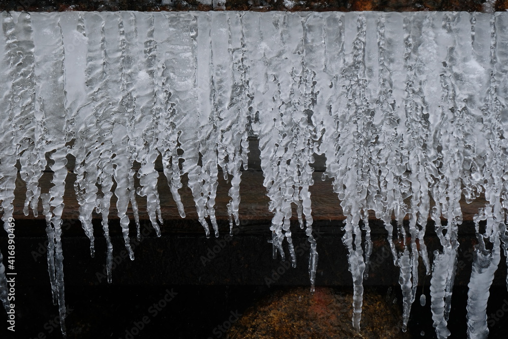 A row of frozen icicles of different lengths and textures A row of frozen icicles of different lengths and textures