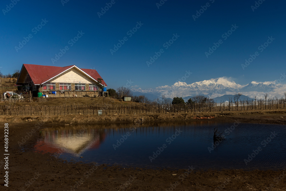 Obraz premium mountA small hut in front of small pond and Kanchenjunga in background.