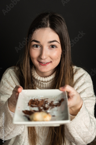 girl offers a plate the last piece of chocolate cream pizza dessert.