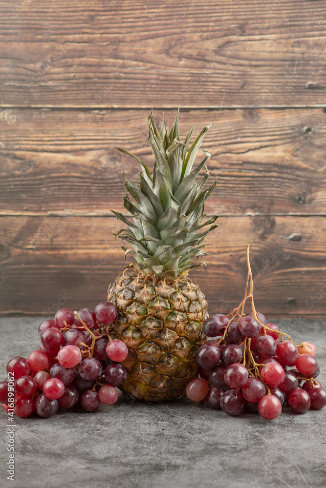Fresh red grapes with ripe pineapple on marble surface Fresh red grapes with ripe pineapple on marble surface