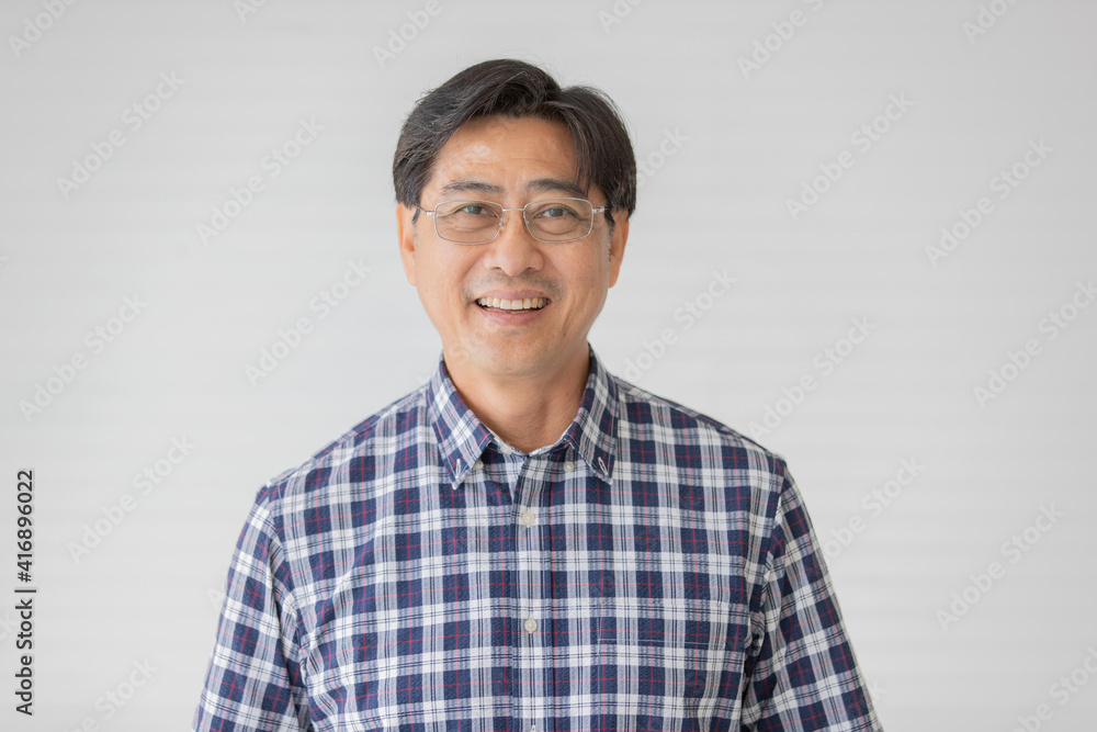 Portrait close up shot of middle aged asian male model with short black hair wearing blue plaid shirt with stand smiling in front of white background Portrait close up shot of middle aged asian male model with short black hair wearing blue plaid shirt with stand smiling in front of white background