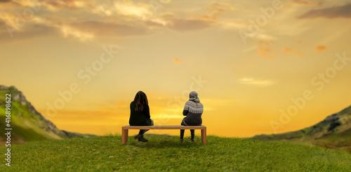 couple sitting on a wooden bench and looking at mountains.