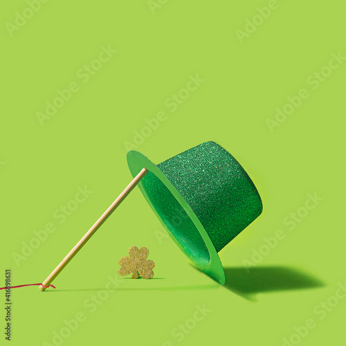 St Patrick concept made of striking green glittery hat and gold glittery shamrock clover. Vivid green creative background