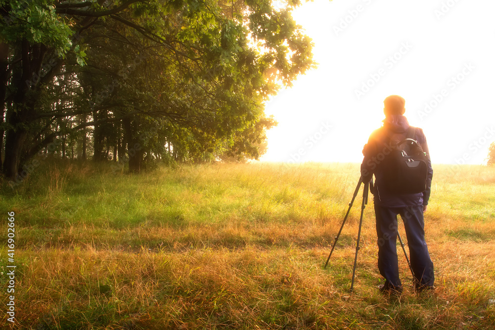 custom made wallpaper toronto digitalA man dreams against vivid sunrise in spring morning. Photographer with tripod enjoys the beautiful scene of wild nature in bright sunlight