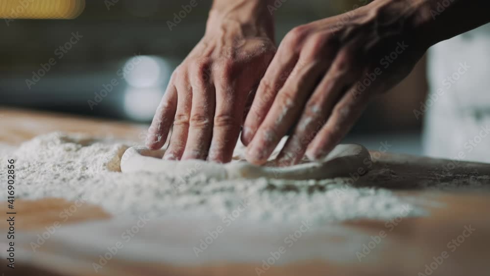 Close up of strong chef's hands forming dough for pizza base in floured wooden table. Competent pizzaiolo preparing ingredients for tasty meal at restaurant. Close up of strong chef's hands forming dough for pizza base in floured wooden table. Competent pizzaiolo preparing ingredients for tasty meal at restaurant.
