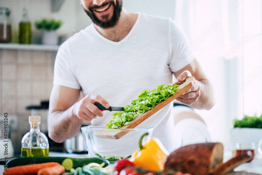 Close up photo of young male hands is preparing wonderful fresh vegan salad in the kitchen at home Close up photo of young male hands is preparing wonderful fresh vegan salad in the kitchen at home