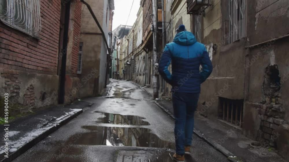 Male person walks alone in street alley with beautiful architecture georgian houses. Traveling solo exploring historical sites and culture Male person walks alone in street alley with beautiful architecture georgian houses. Traveling solo exploring historical sites and culture